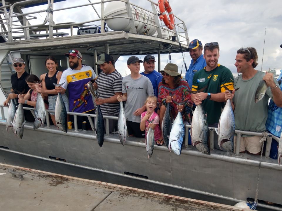 fathers-day-present-ideas Group fishing trip with multiple people holding freshly caught fish as one of the fathers day present ideas.